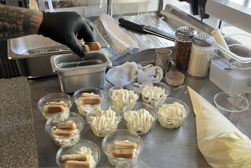 Manager Jackson Zheng, 26, dips lady fingers into homemade coffee mixture and places them atop a bed of mascarpone creme to create tiramisu. He then topped the dessert with additional creme and cocoa powder.