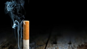 Cigarette crushed out on a rustic wooden table top.