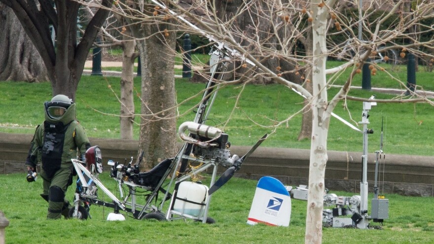 An Explosive Ordnance Disposal Technician and a robotic police device check Hughes' gyrocopter after it on the South Lawn of the Capitol.