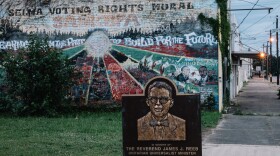 A memorial to the Rev. James Reeb, attacked near this site in 1965, stands in front of a faded civil rights mural in Selma, Ala.