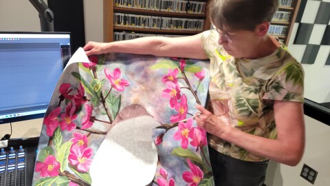 A person holding a piece of colorful fabric art