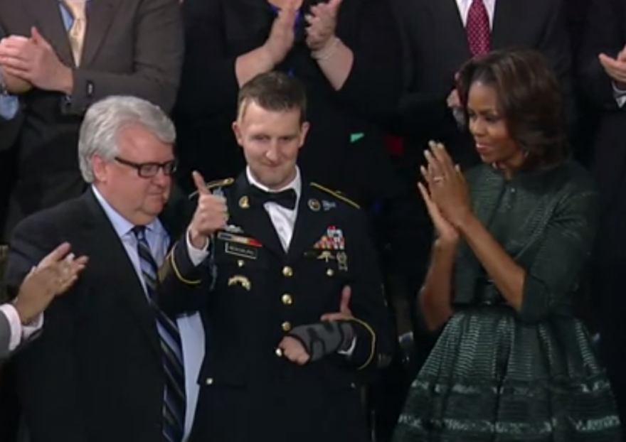 Cory Remsburg, flanked by his father, Craig, and First Lady Michelle Obama, responds to the ovation Tuesday night.