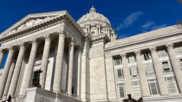 The front of the Missouri state capitol building. Columns, a statue and the dome are visible. 