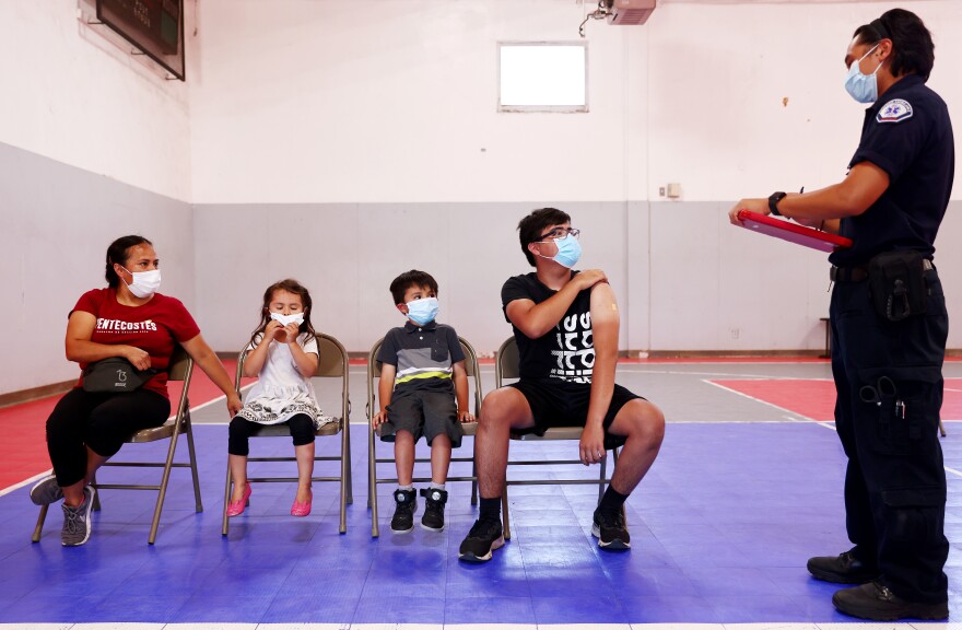 Accompanied by his family, a student gets vaccinated at a pop-up COVID-19 vaccination clinic on Tuesday in Winnetka, Calif.