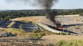 fire at a landfill with plume of black smoke