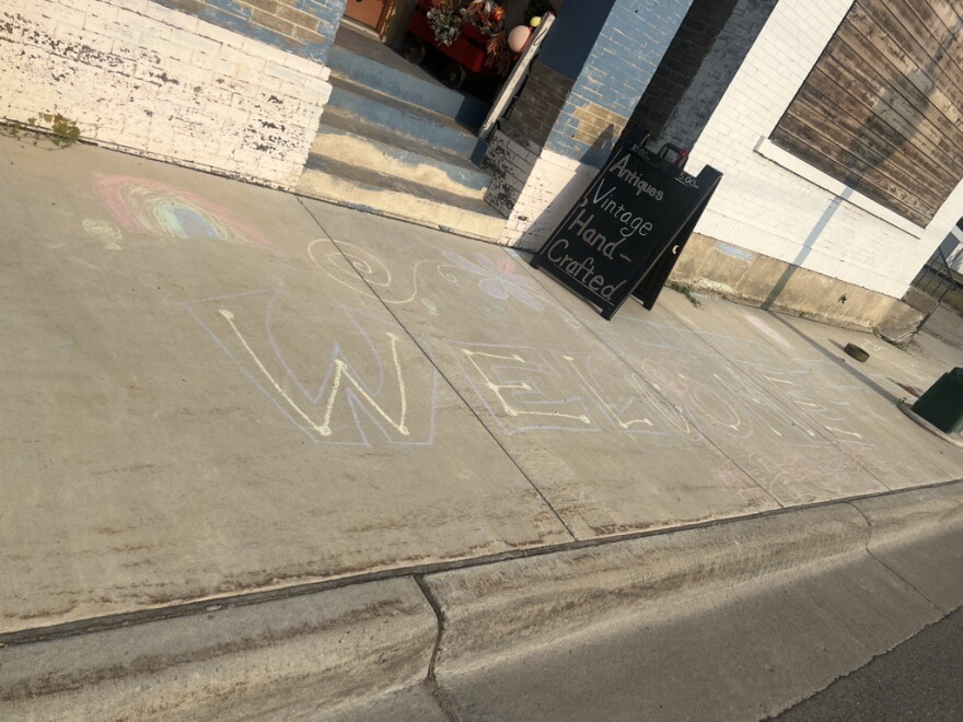 "Welcome" is written in sidewalk chalk in front of a store. 