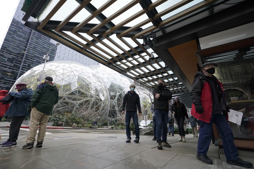People wait in line near the Amazon Spheres as they wait to check in to receive the first of two doses of the Pfizer vaccine for COVID-19 at a one-day vaccination clinic set up in an Amazon facility in Seattle.
