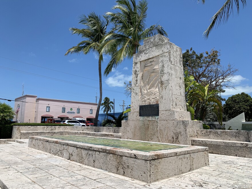 A concrete historical marker with a palm tree next to it