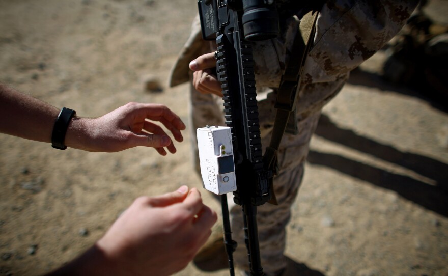A Marine places a testing device on the barrel of a weapon before a live-fire exercise.