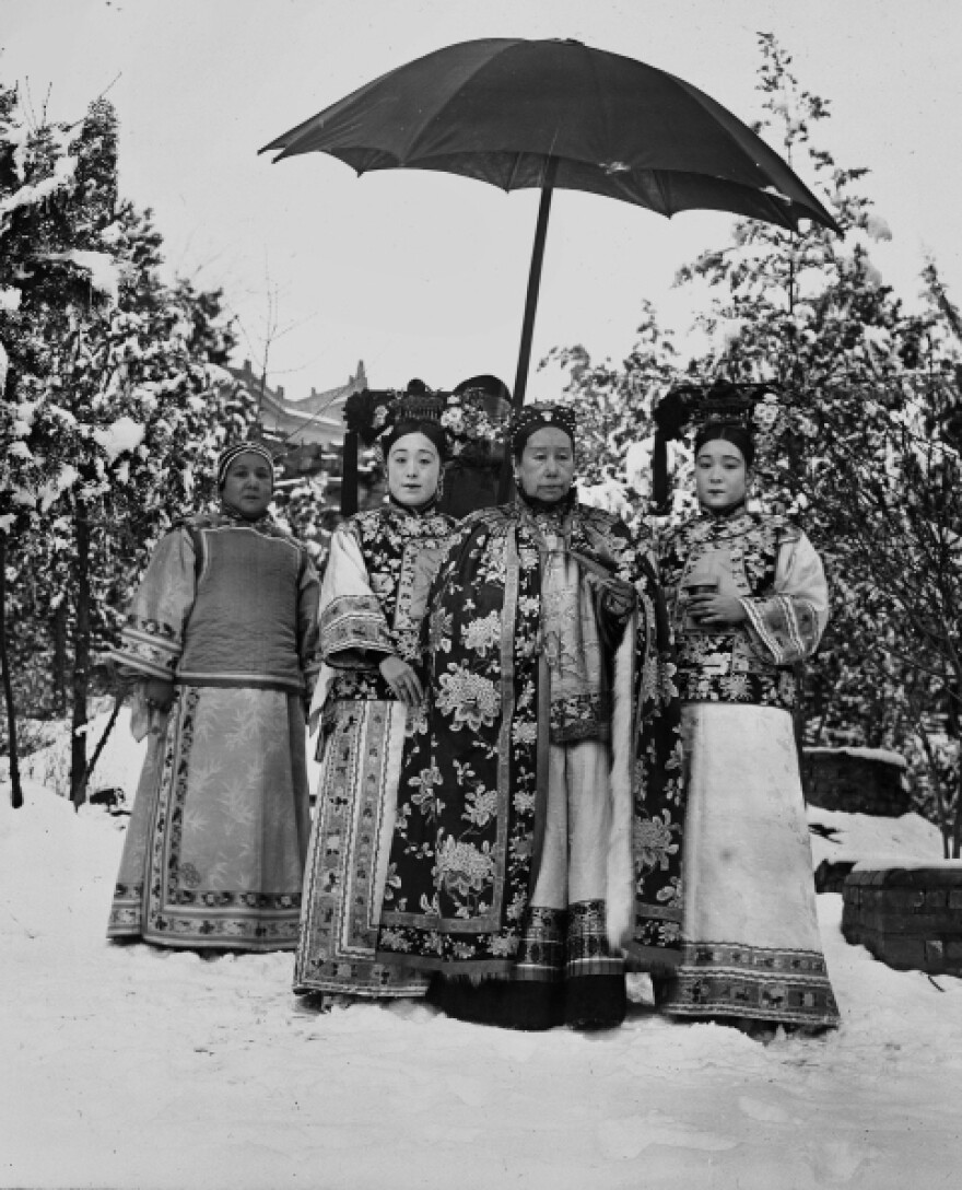 Cixi, accompanied by her attendants, stands in the snowy gardens of Wanshoushan (Longevity Hill), the central hill of the Summer Palace. The image is one of nine similar photographs that were most likely taken for the enjoyment of the empress and her attendants — not for any diplomatic purpose.