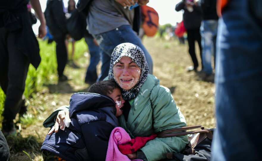 A woman and her children cry after being affected by tear gas near Idomeni on Sunday. Hundreds of people were hurt when police fired tear gas on a group of migrants as they tried to break through a fence on the Greece-Macedonia border, Doctors Without Borders said.