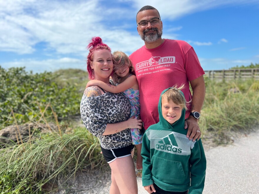 Woman and man stand with their children, a young girl and a boy in front of a sand dune.