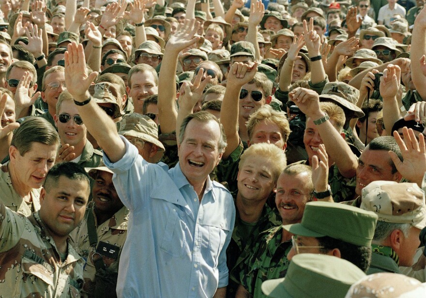 Bush poses with soldiers during a stop at an air base in Dhahran, Saudi Arabia, on Nov. 22, 1990.