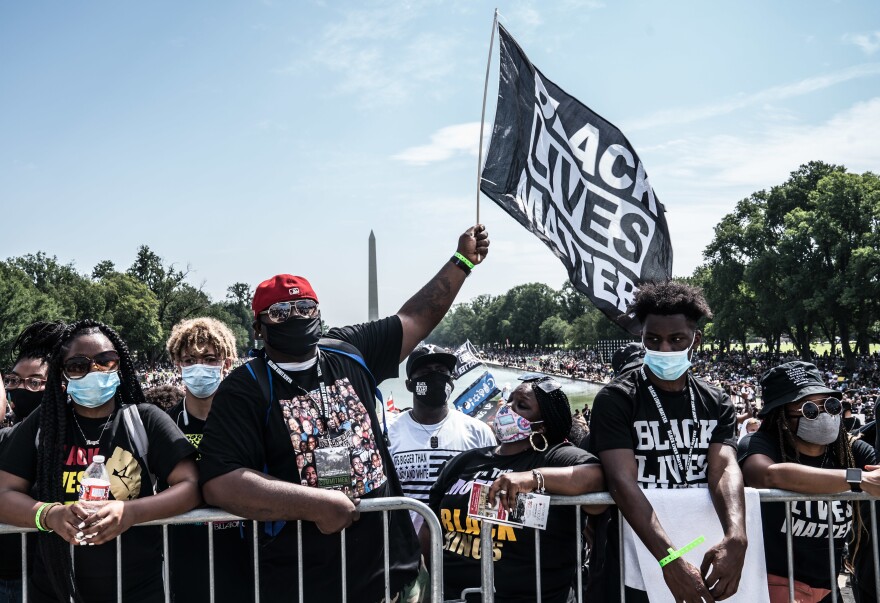 People wait for the speakers to start around the Lincoln Memorial Reflecting Pool.