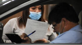 A human resources representative reads a resume at a drive-thru job fair in Elkhart.