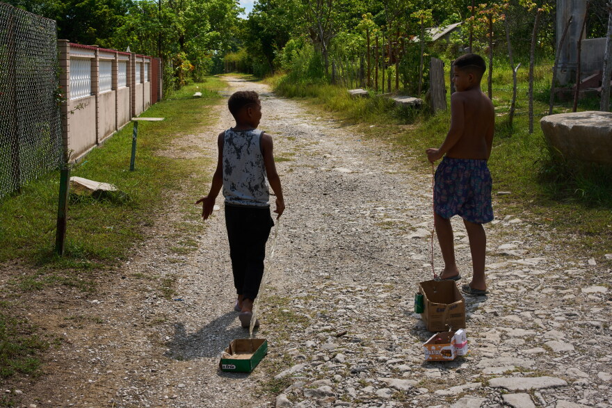 Children drag toys made from cardboard boxes as they walk in Minas, in Cuba's Havana province, Monday, Aug. 31, 2026.