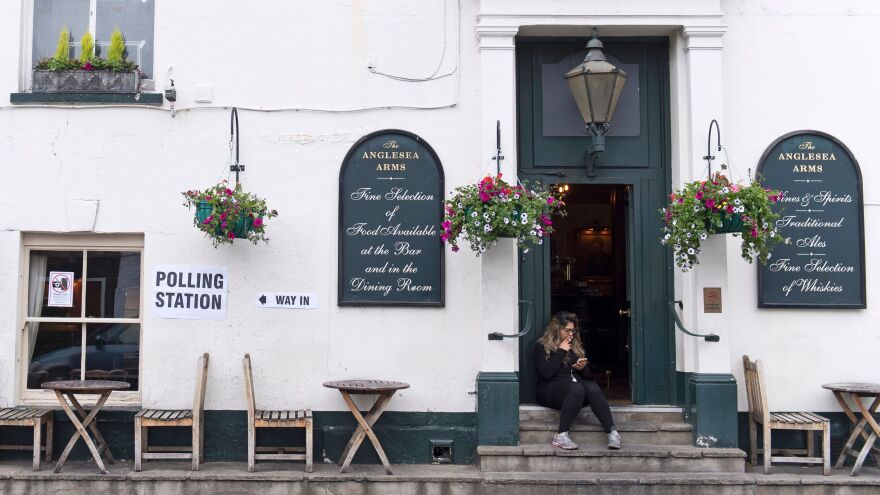 A woman sits outside the Anglesea Arms pub, set up as a polling station during Britain's general election, in London on Thursday.