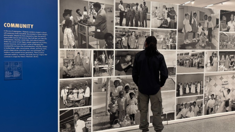 A man stands in front of a wall of photos at the Rhythm and Resilience: Black Vegas exhibition.