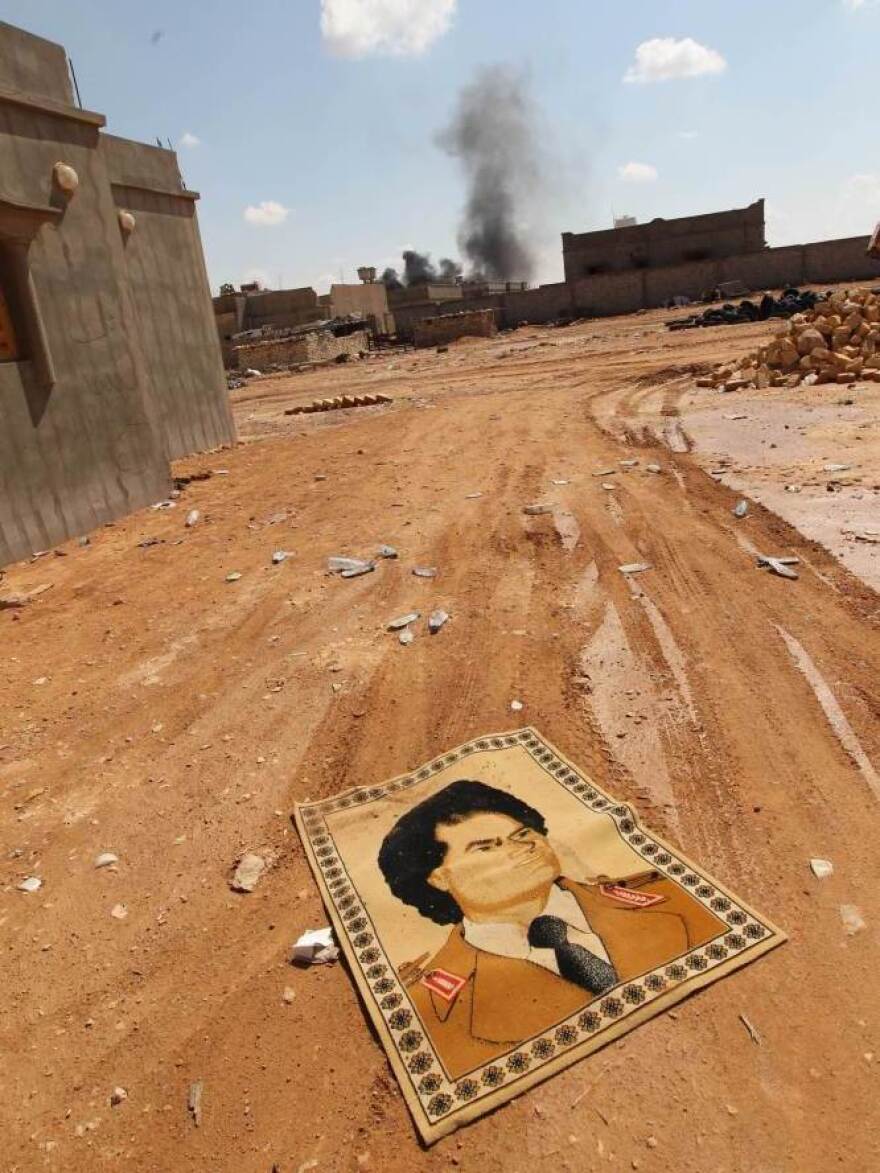 <p>A small carpet with the portrait of Gadhafi lies on the ground near fighting at the front line of Bani Walid, southeast of Tripoli, earlier this month.</p>