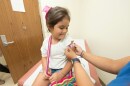 A little girl in a doctor's office receives a colorful bandaid on her arm after a shot. 