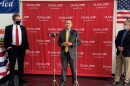 Mayor Curry standing and speaking in front of a large GOP sign, Rutherford and Black off to the side of him