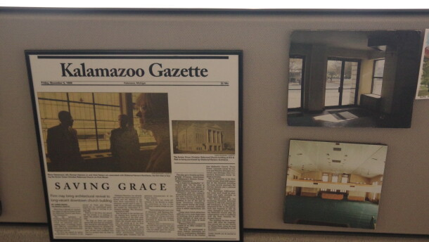 A newspaper clipping along with photos of what the church looked like before the renovations hang on the side of a desk. The tagline "Saving Grace" can be seen on the newspaper, which is framed along with the two photos.