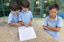 Warren Li (right) is being quizzed by twin brothers Benji and Charlie from a Scripps National Spelling Bee study guide.