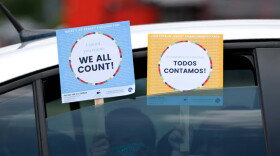 FILE: Two young children hold signs through the car window that make reference to the 2020 U.S. Census as they wait in the car with their family at an outreach event in Dallas, June 25, 2020.