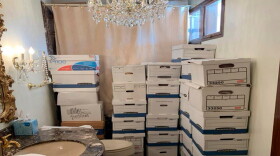 A room with white cardboard boxes filled with documents stacked high.