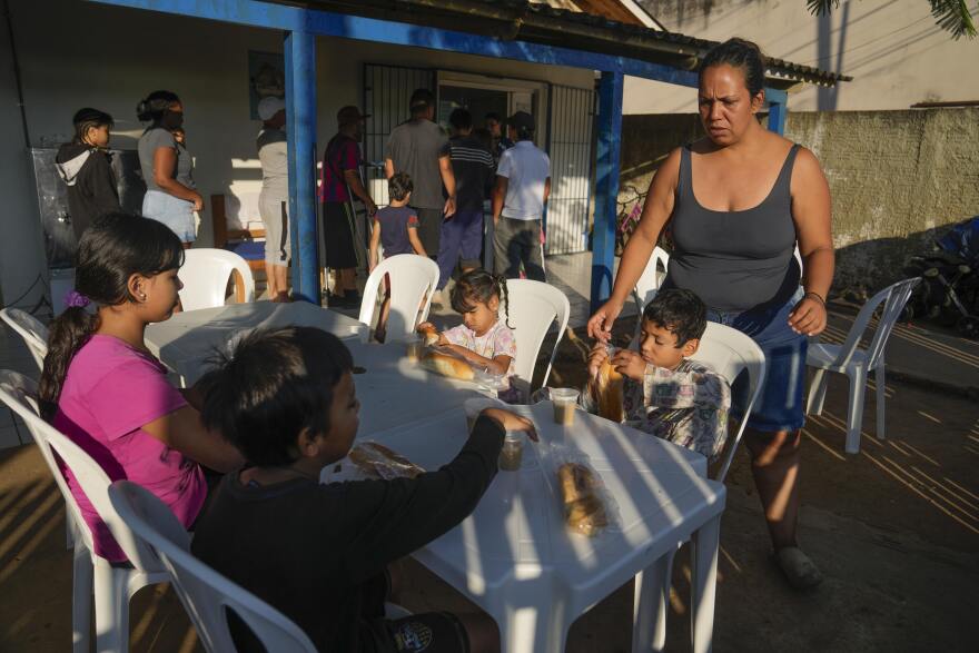 Venezuelan migrant Natalia Contreras tends to her children as they settle in to have breakfast at a shelter in Rio Branco, Brazil, Saturday, June 22, 2024.