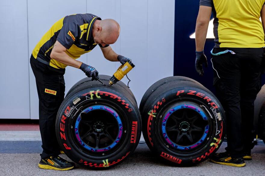 Pirelli team members work on the Alpine tires after the second practice session.
