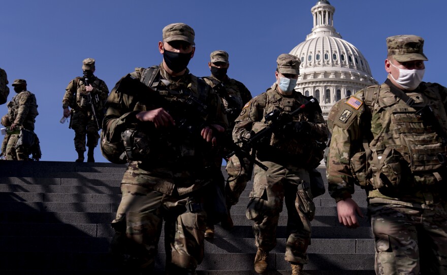 Members of the National Guard walk past the Capitol in Washington on Thursday. By next week, they will be joined by thousands of others.