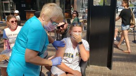 Mika Turner gets her first dose of the Pfizer vaccine while watching the Bucks game outside the Fiserv Forum at the jumbo screen.