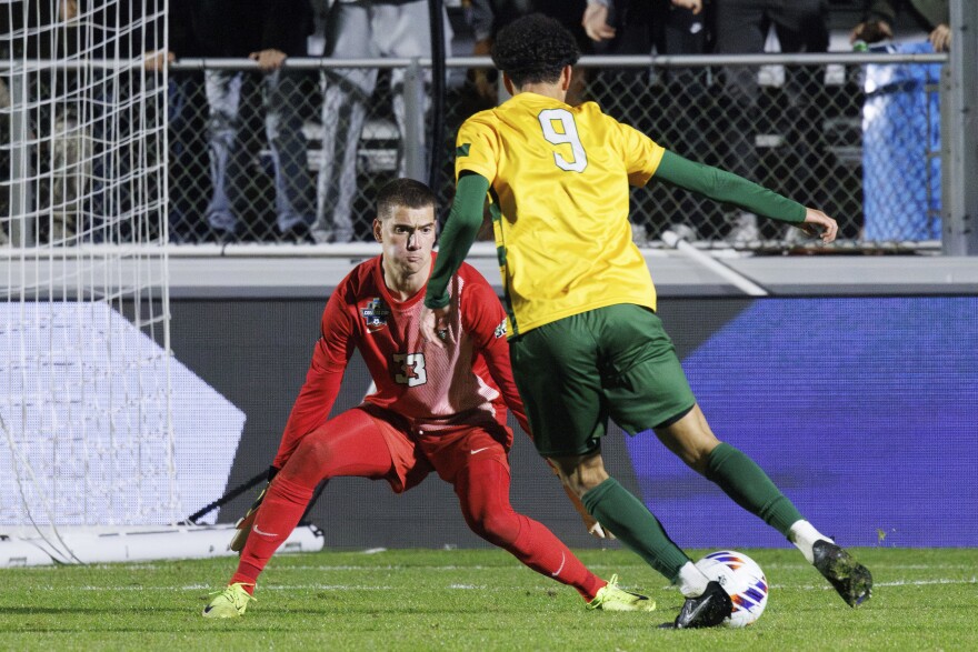 A soccer goalkeeper defends against another player moving ahead with the ball