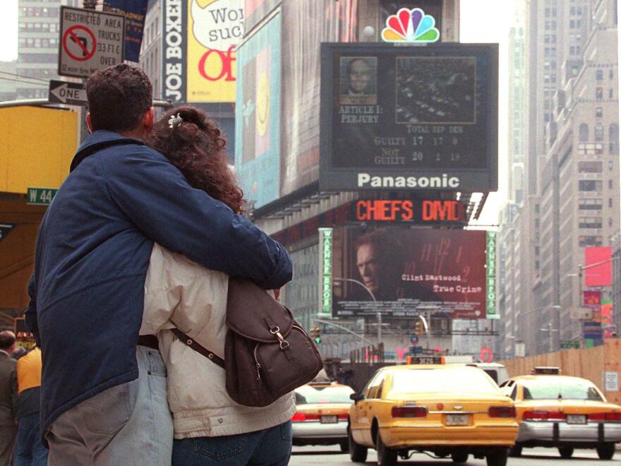 Isabelle and Israel Cerutti of Brazil hug as they watch the NBC jumbotron in Times Square display the "Not Guilty" verdict on the Obstruction of Justice charges against US President Bill Clinton during his impeachment trial on Capitol Hill in 1999.