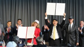 Purdue and Indiana University Presidents Mung Chiang and Pamela Whitten hold up the official agreement to dissolve IUPUI.