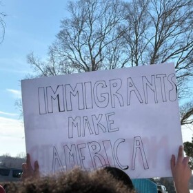 A student holds up a sign that says "Immigrants Make America" during a walkout protest against ICE in Derby.