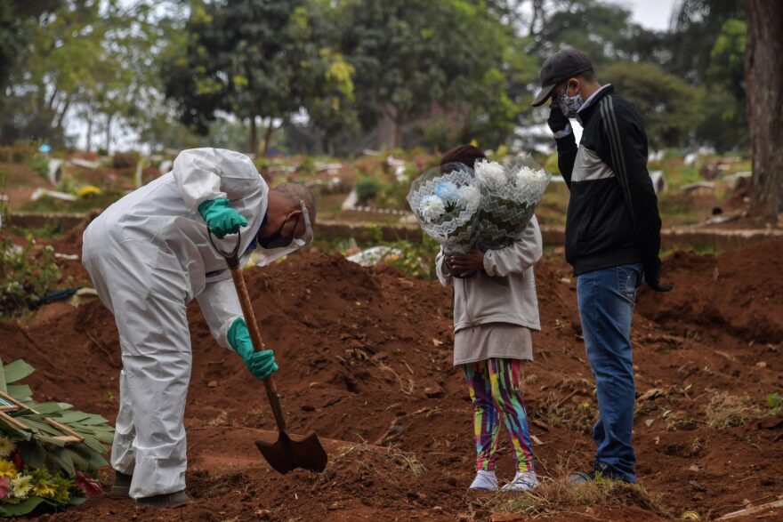 An employee digs next to relatives of a person who died from COVID-19 at the Vila Formosa cemetery, in the outskirts of Sao Paulo, Brazil.