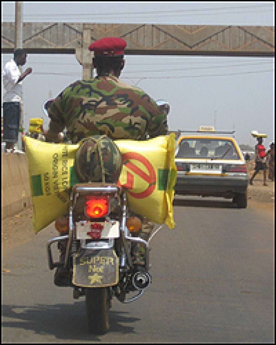 A soldier on a motorcycle carries a bag of rice through the streets of Conakry. "Last year, Guineans were fighting for the bag of rice," says political commentator Souleymane Diallo. "Now they are fighting for a plate of rice."