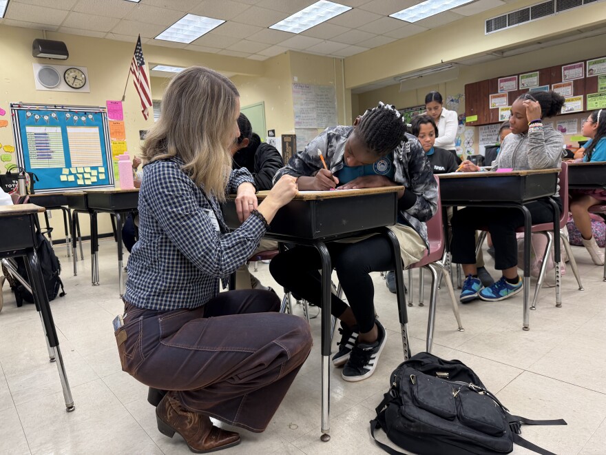 Cabrera goes around the room to gelp students write their poems.