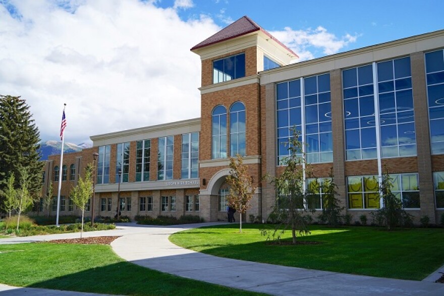 Multi-story, tan brick school building with large windows.