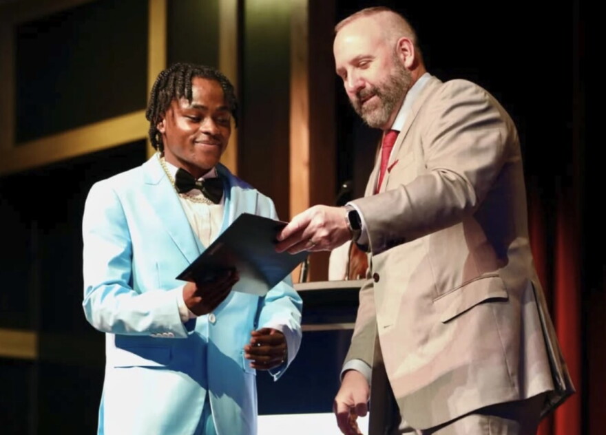 teen in suit receives a document from another man in suit