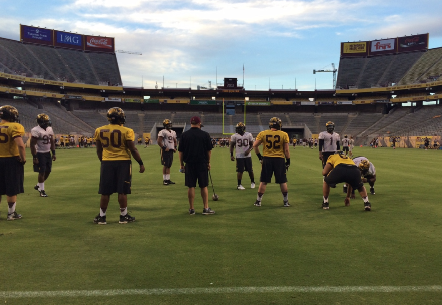 Members of the ASU football team practice inside Sun Devil Stadium with the renovated north end zone in the background.