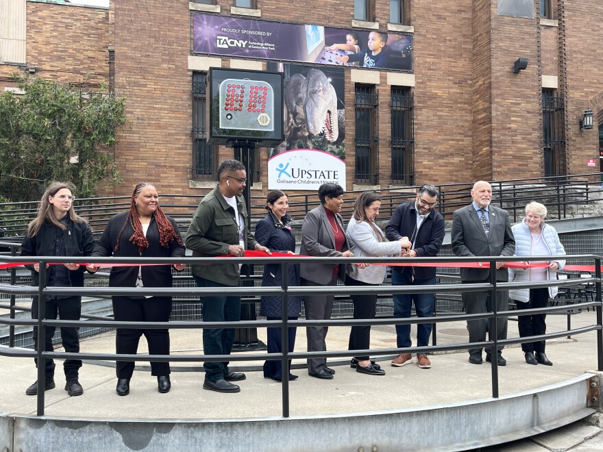 City officials and relatives of Leo Ferris and Danny Biasone cut the ribbon on the new location of the shot clock behind them.