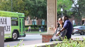 Graduate students Simon Suuk and Julia Taylor wait at one of the RTS bus stops on the University of Florida campus.