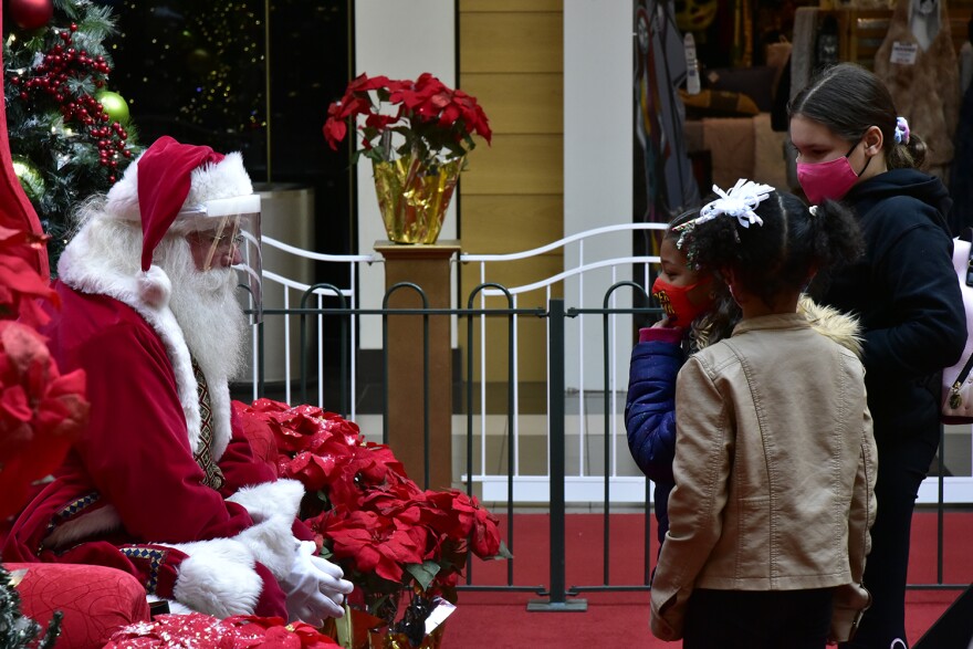Santa, wearing a face shield, speaks with children wearing cloth face masks at the University Park Mall in Mishawaka.