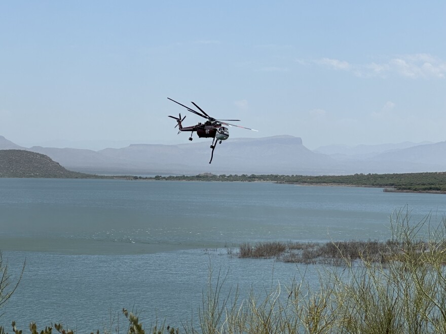 A helicopter gathers water to fight the Black Fire east of Phoenix on July 15, 2024.