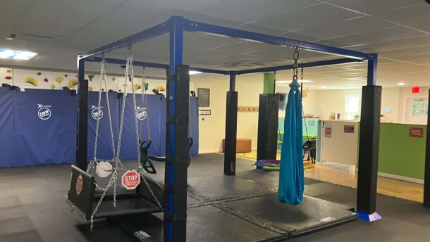 Several different types of indoor swings attached to metal beams with padding underneath.
