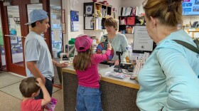 Delta Community Library Director Tiki Levinson, behind the counter, helps another family get rewards for reading.
