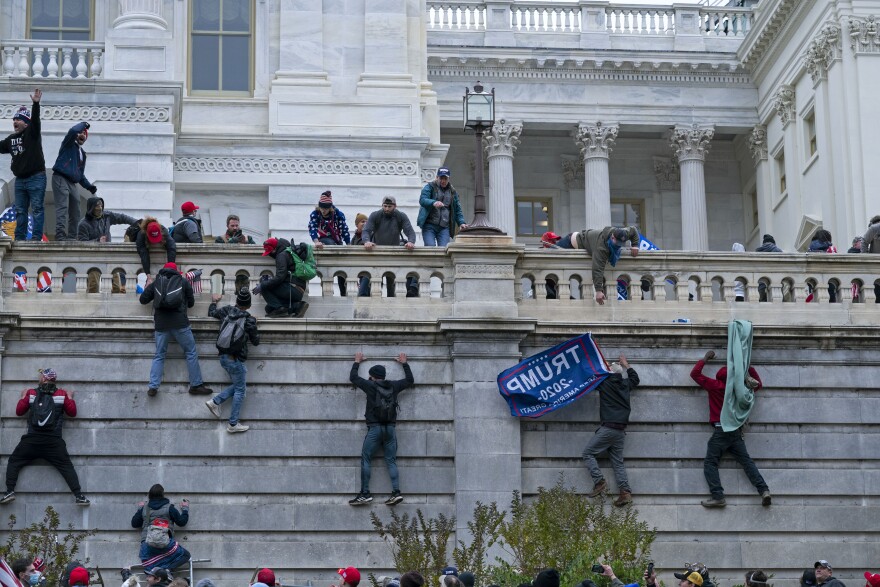 Supporters of President Donald Trump climb the West wall of the the U.S. Capitol.